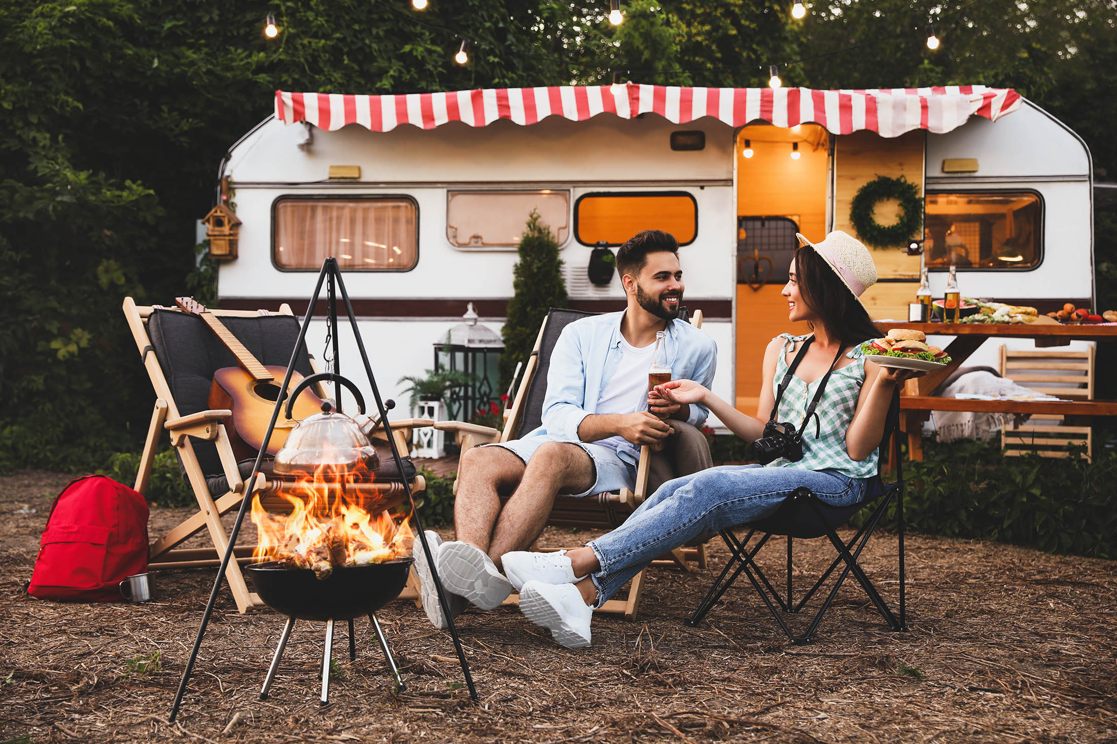 Happy couple resting near trailer. Camping season